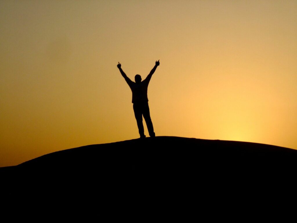 a person standing on top of a hill with their arms in the air